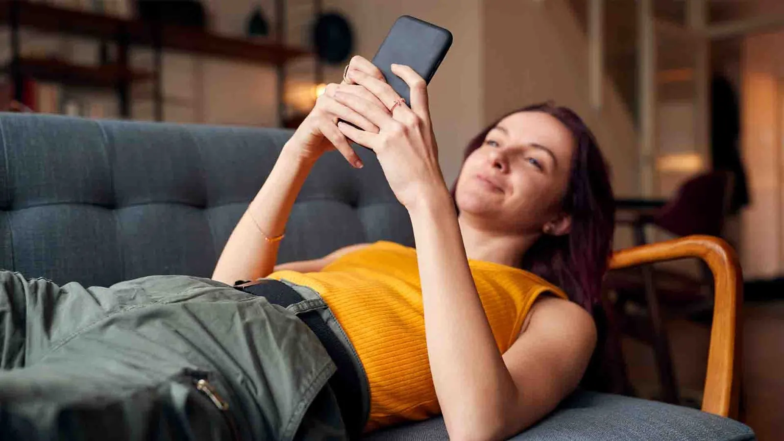 Woman scrolling phone on couch